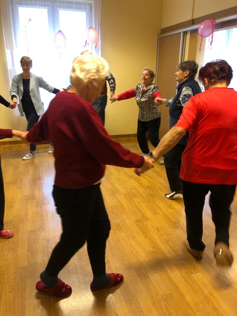 Seniorzy tańczą w kółku za ręce
