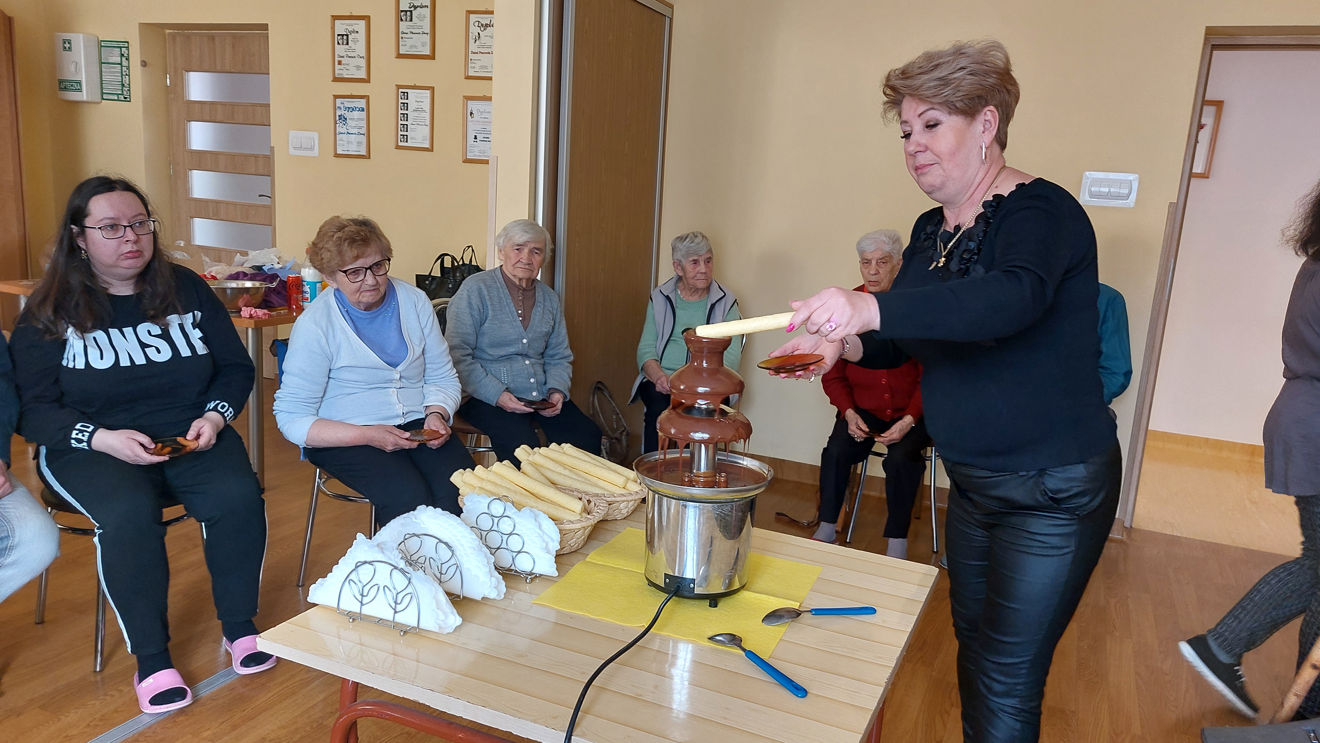 Pani Dorota macza chrupka kukurydzianego w czekoladzie.