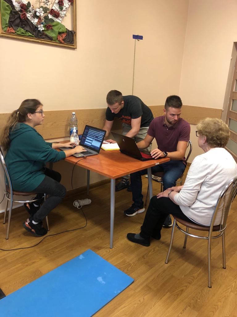 Troje studentów z Koła naukowego wpisują wyniki na laptopach, przy ich biurku siedzi Seniorka