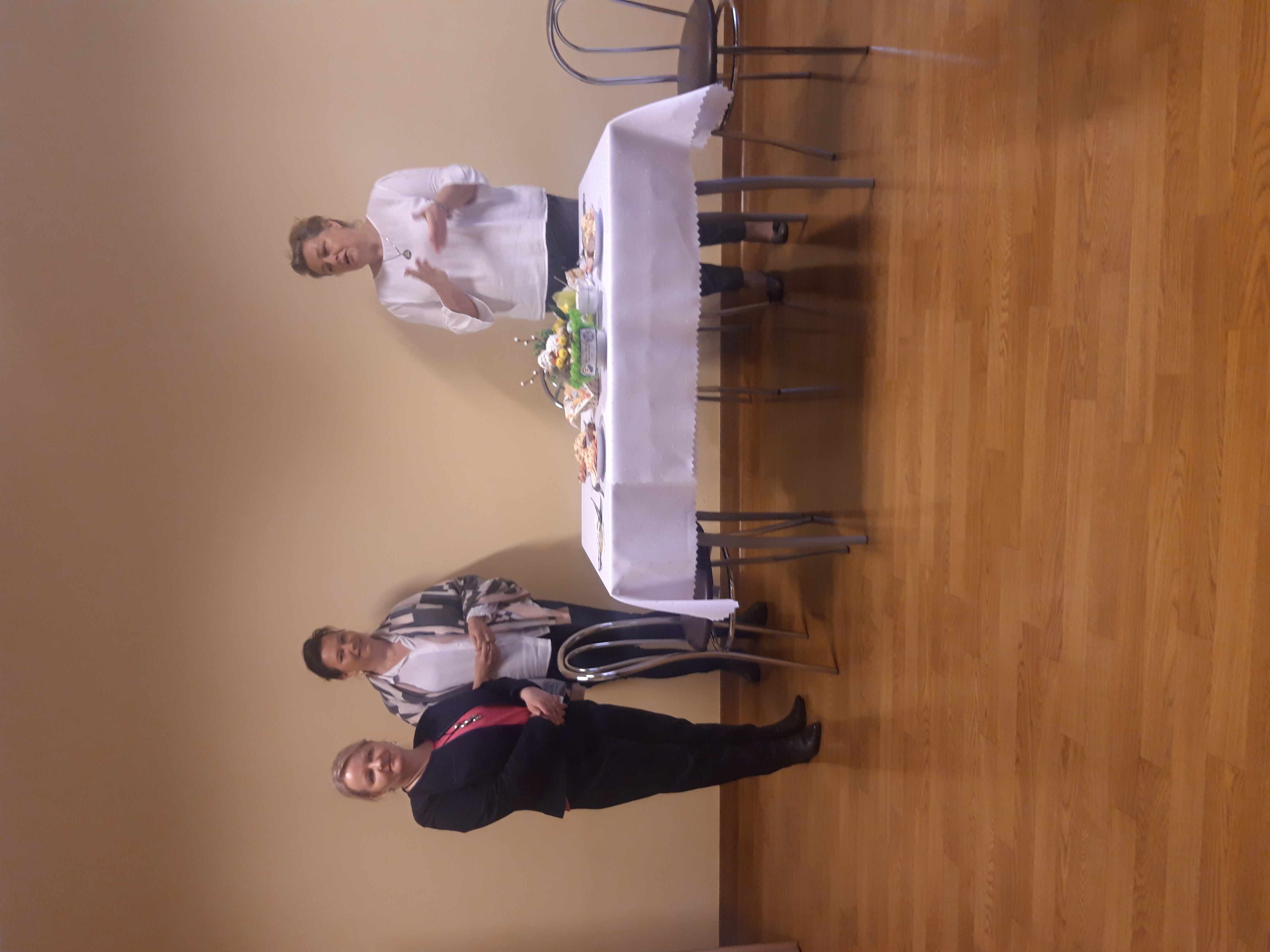 Dyrektor DPS, Agnieszka Sokorska,kierownik DTO oraz kierownik Dziennego Domu stoją przy stole i składają życzenia