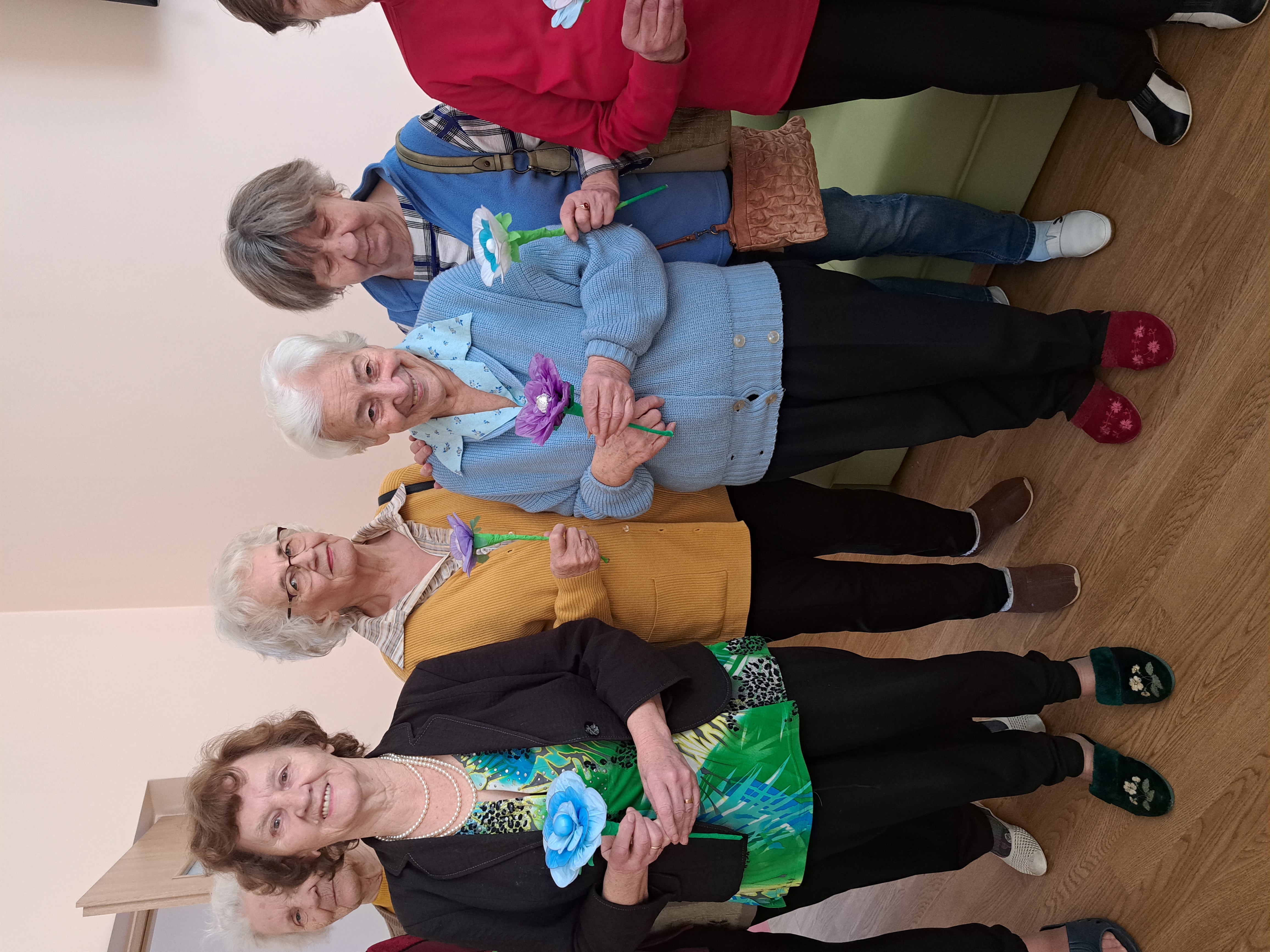 Grupa Seniorek pozuje z ręcznie zrobionymi kwiatami