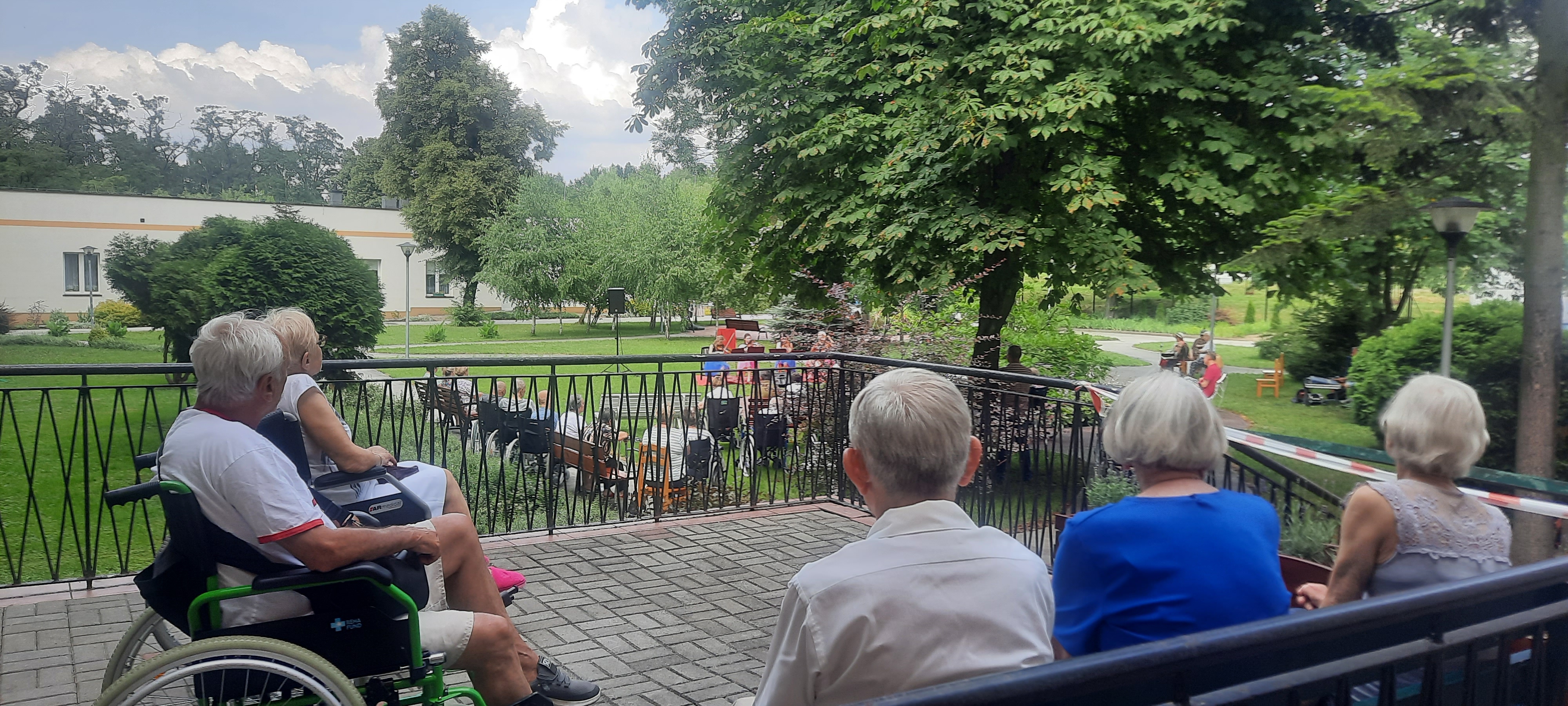 Seniorzy oglądają występ, siedząc na tarasie