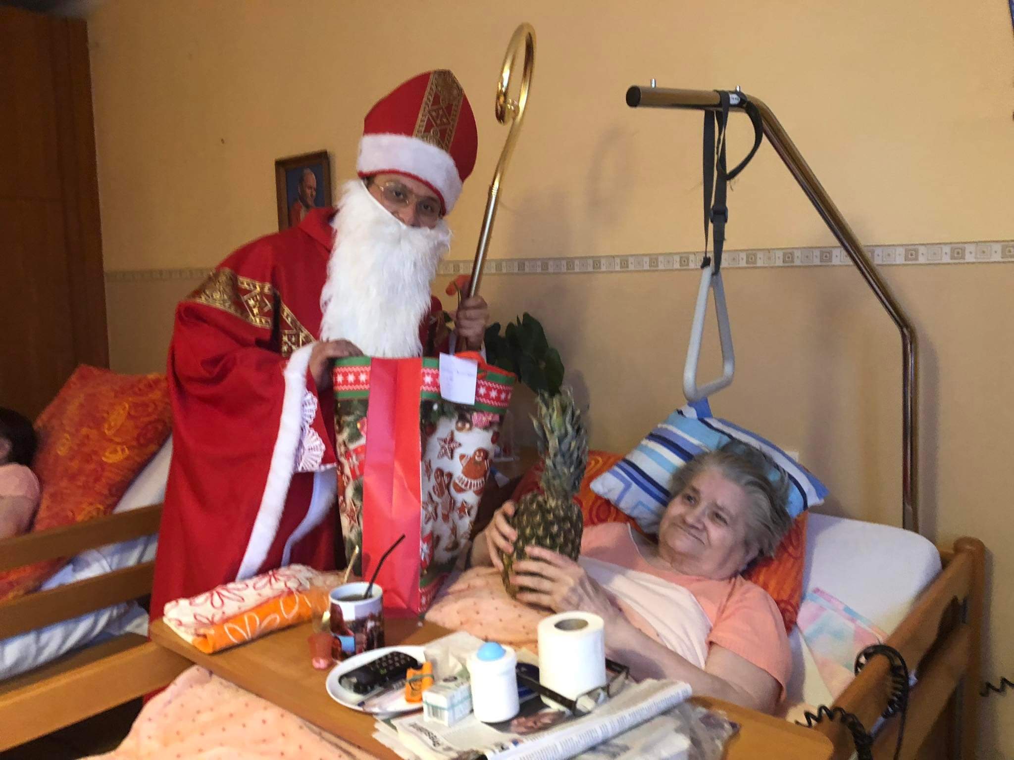 Mikołaj wręcza prezent Seniorce. Seniorka trzyma ananas w rękach