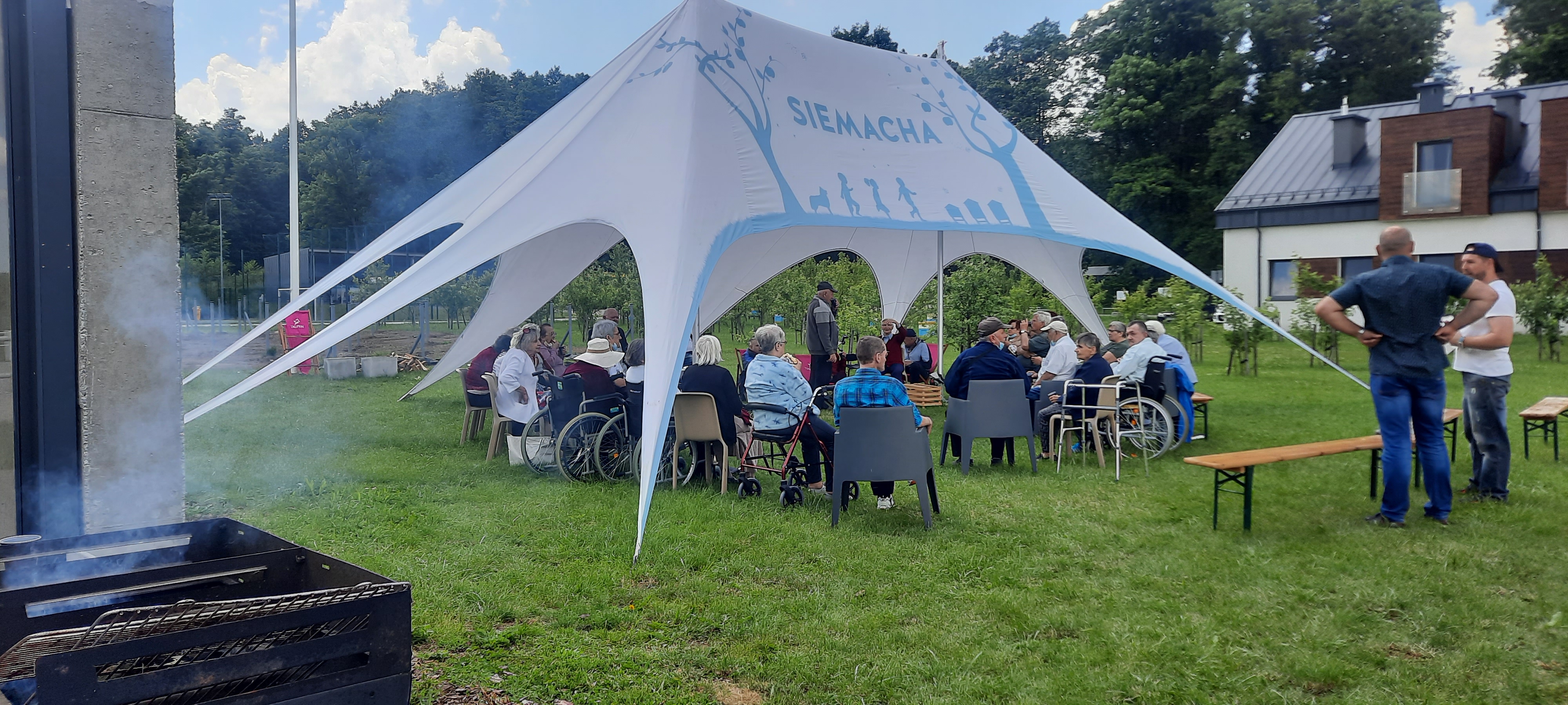 Seniorzy siedzą na polu pod zadaszeniem