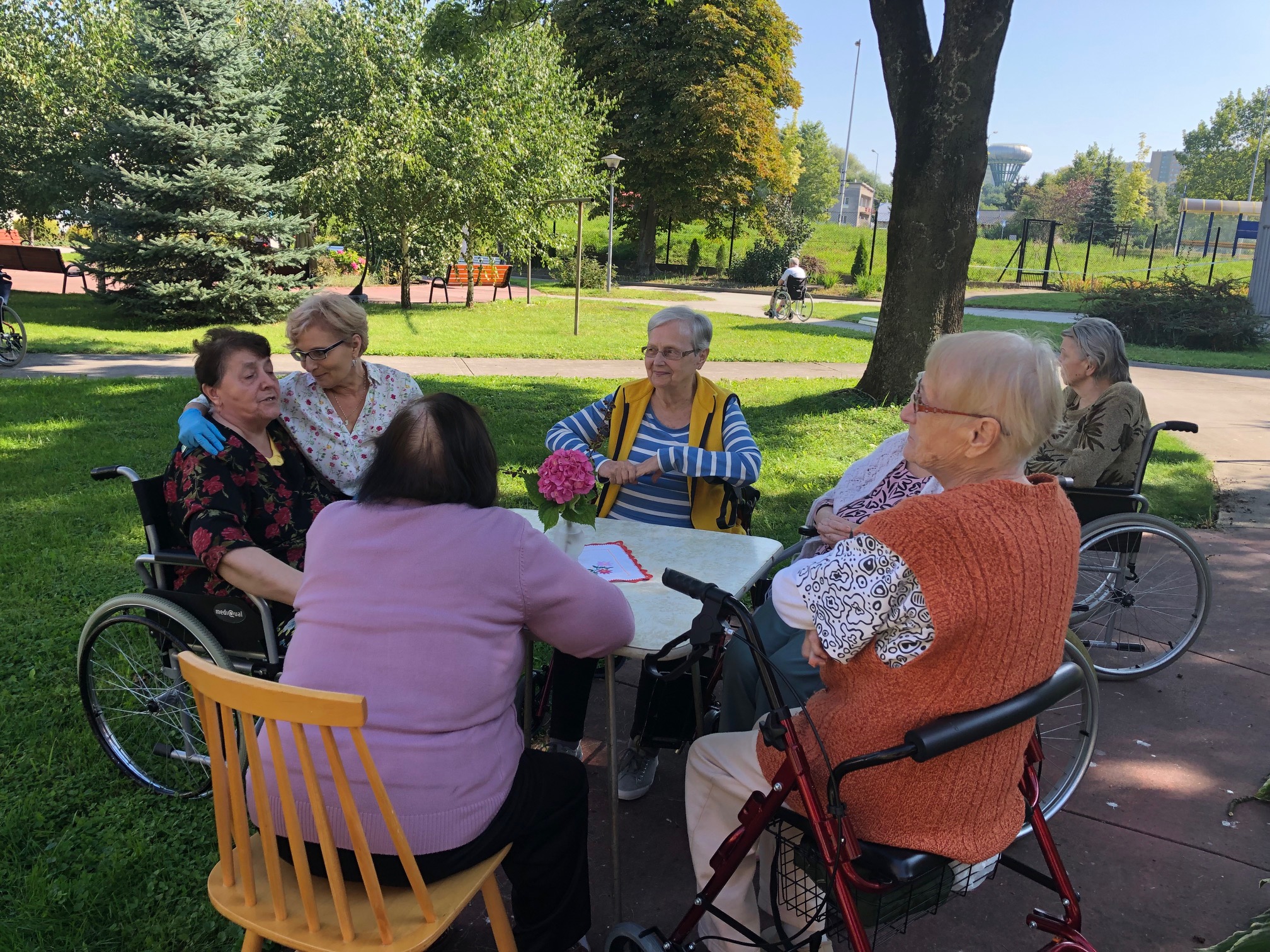 Seniorzy siedzą na polu pod zadaszeniem