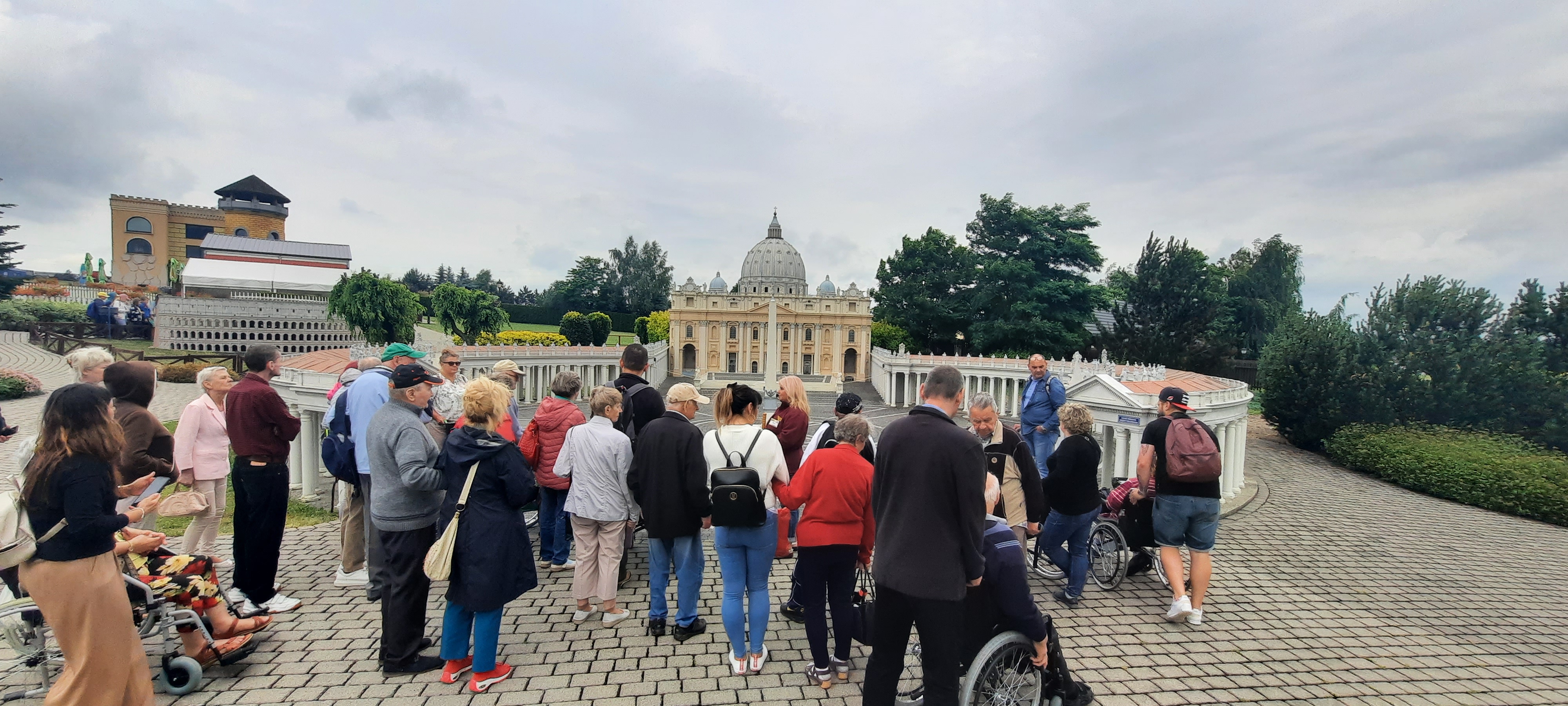 Wycieczka zebrana w półokrąg ogląda miniturową świątynię