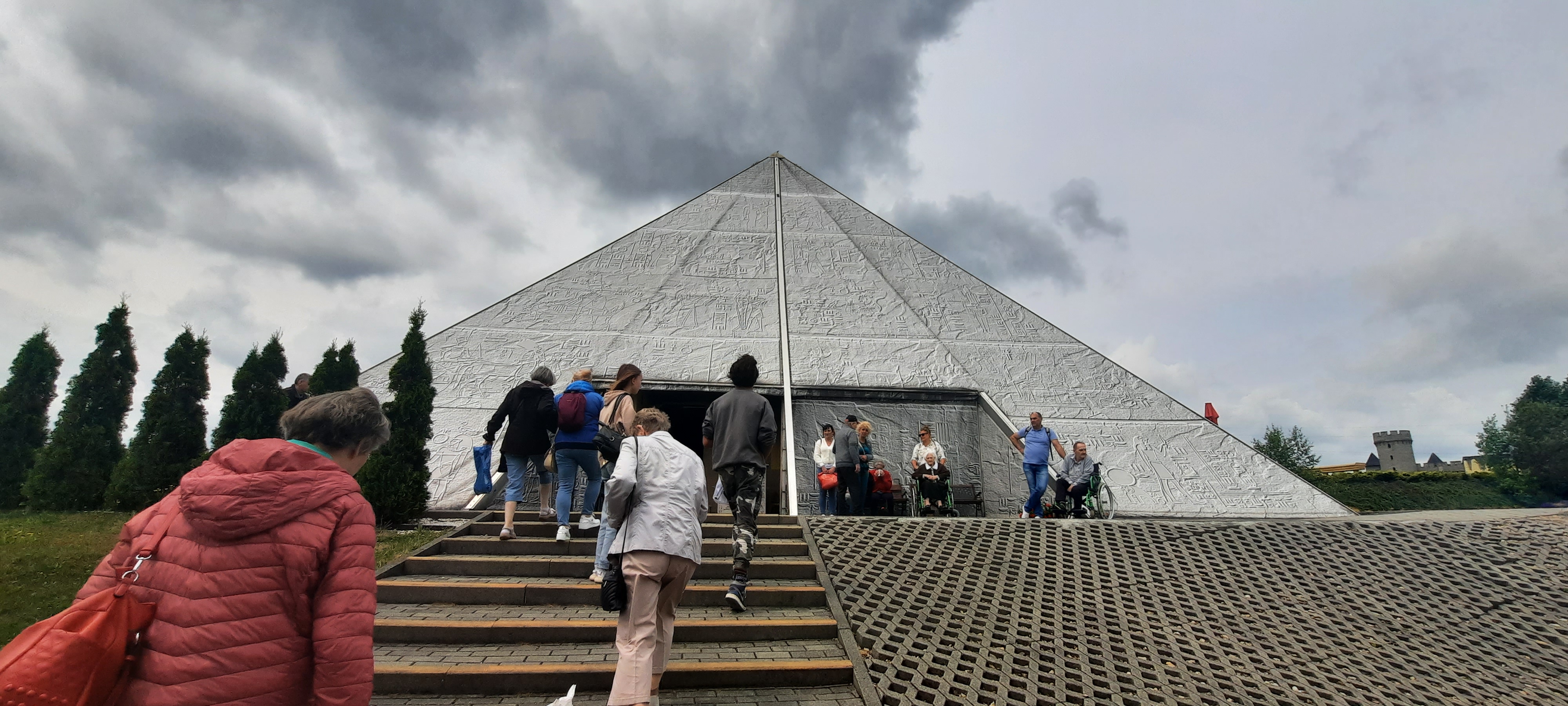 Wycieczka wchodzi po schodach do repliki piramidy