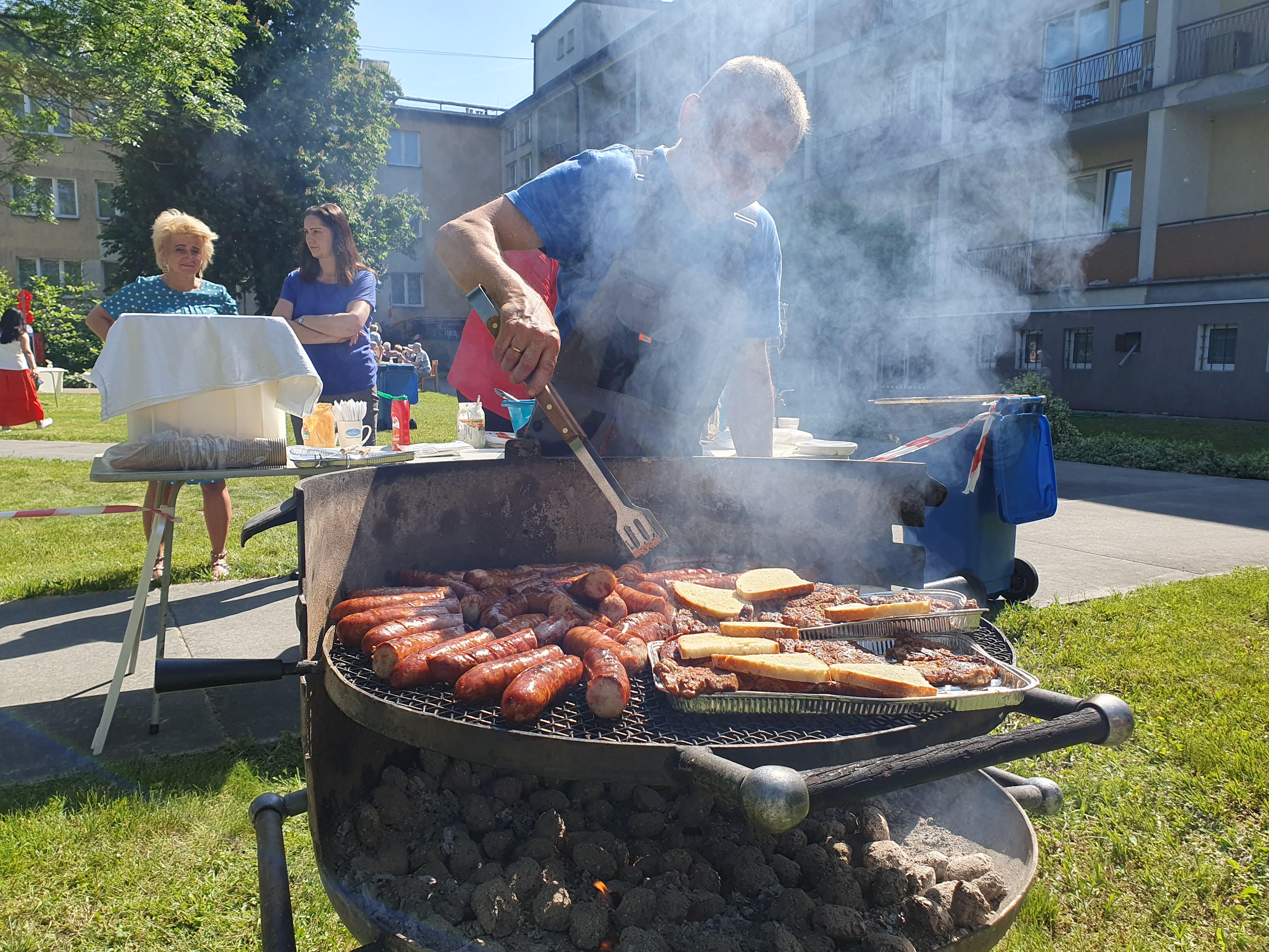 Ujęcie na pracownika DPS przygotowującego kiełbaski na grillu