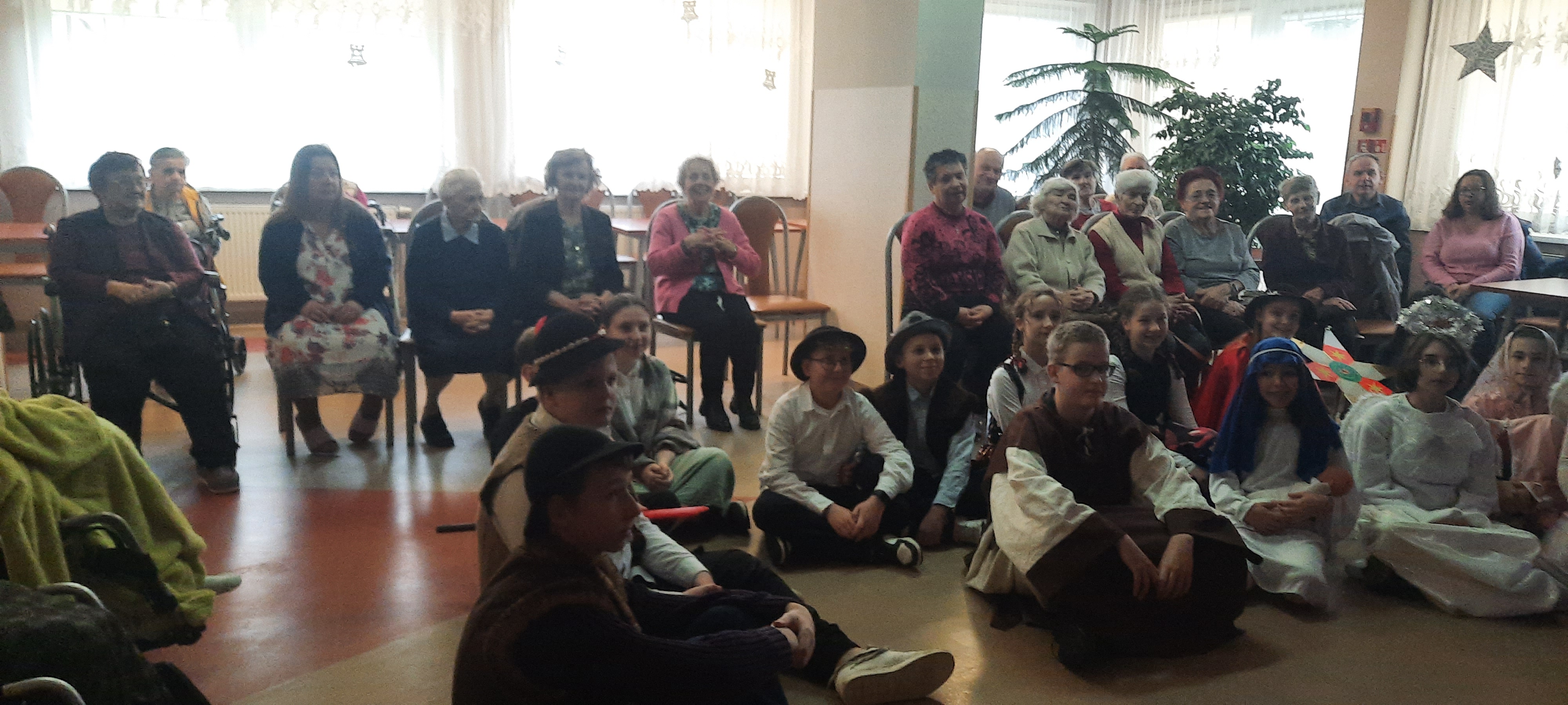 Seniorzy oglądają występ dzieci prezentujących Jasełka