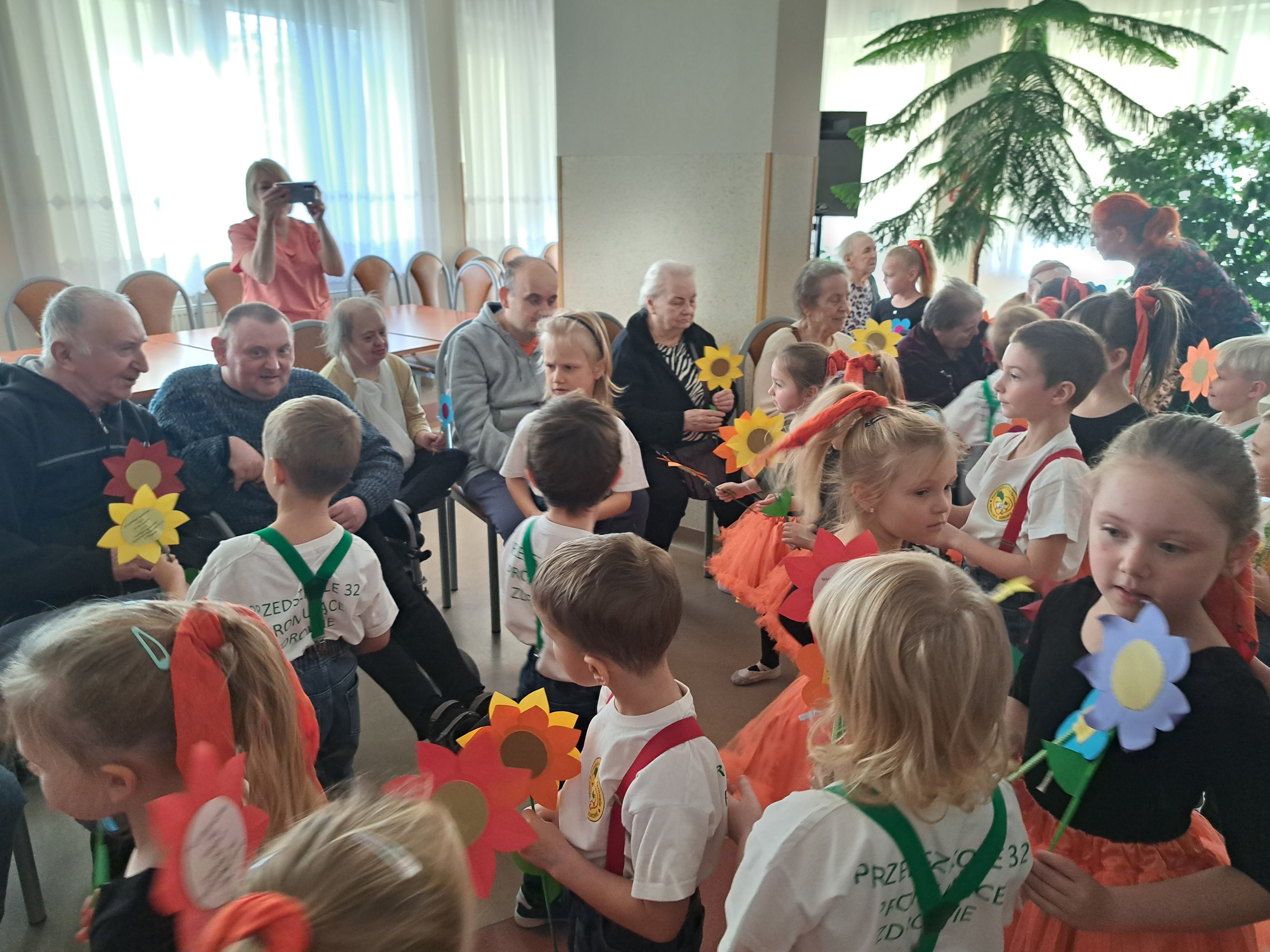 Dzieci wręczają Seniorom, zrobione przez siebie papierowe kwiatki