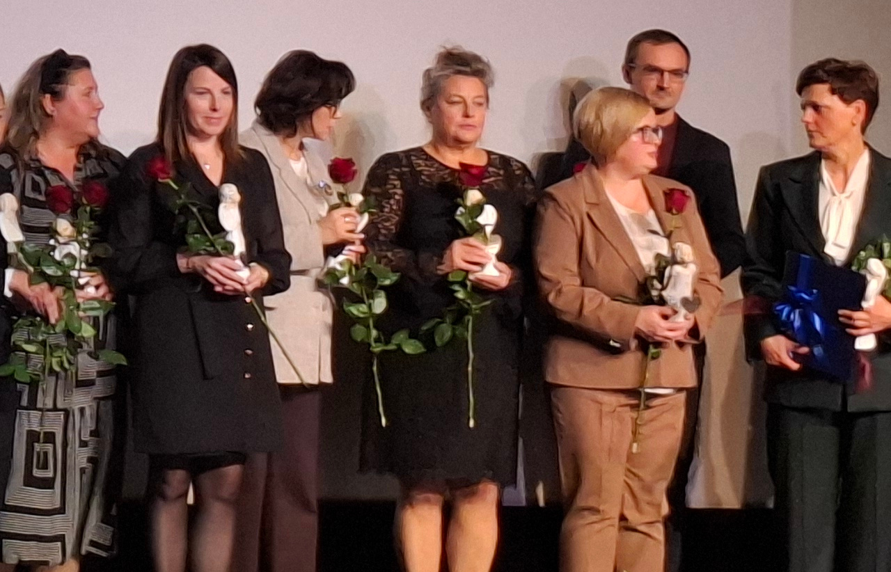 Pracownicy Socjalni stoją na scenie z różami w rękach