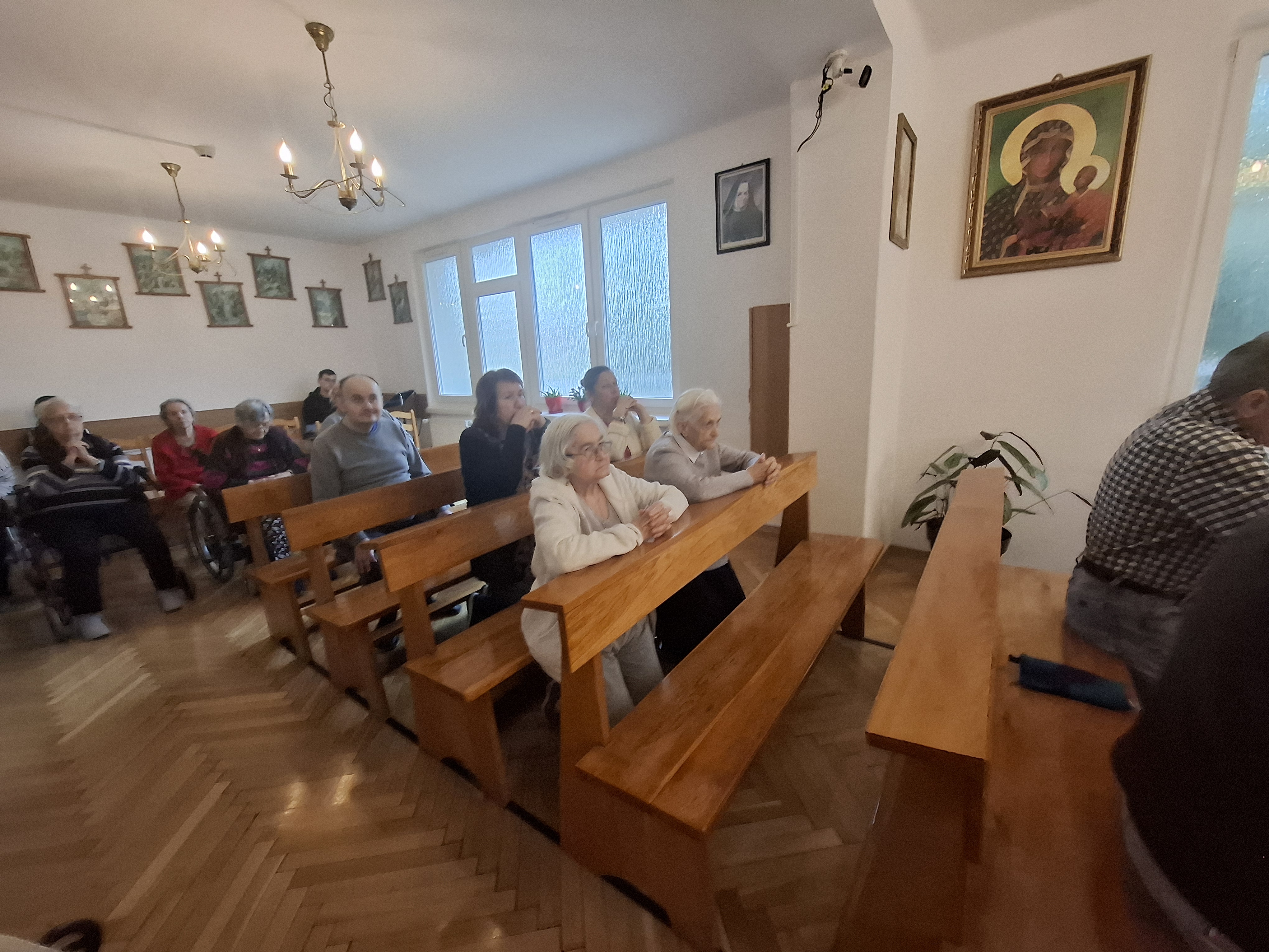 Seniorzy siedzą przy stole, jedzą ciasteczka i piją kawę