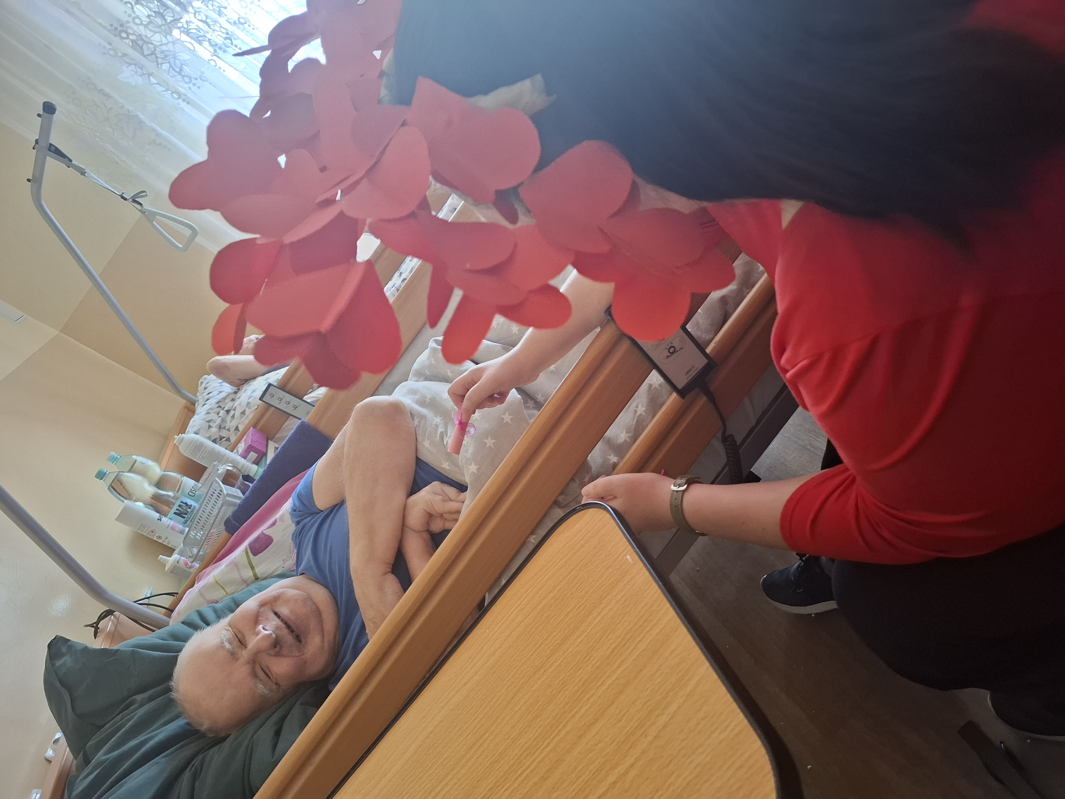 Seniorzy siedzą przy stole, jedzą ciasteczka i piją kawę