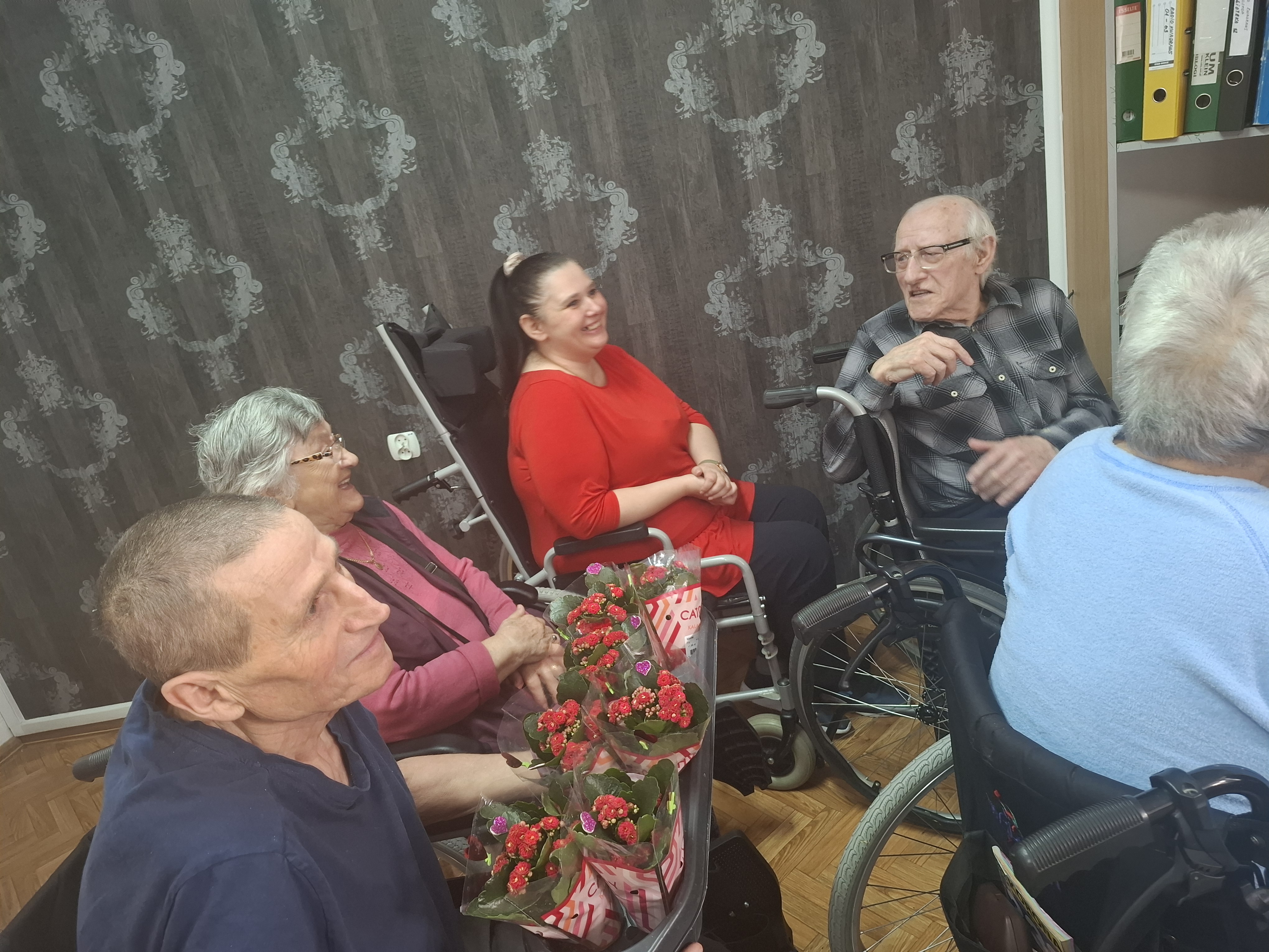 Seniorzy siedzą przy stole, jedzą ciasteczka i piją kawę